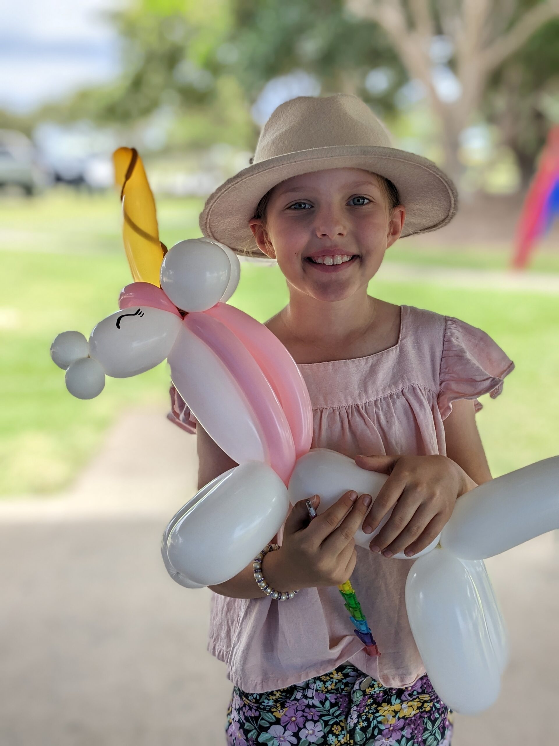Entertainer and child pose together with a large balloon rainbow