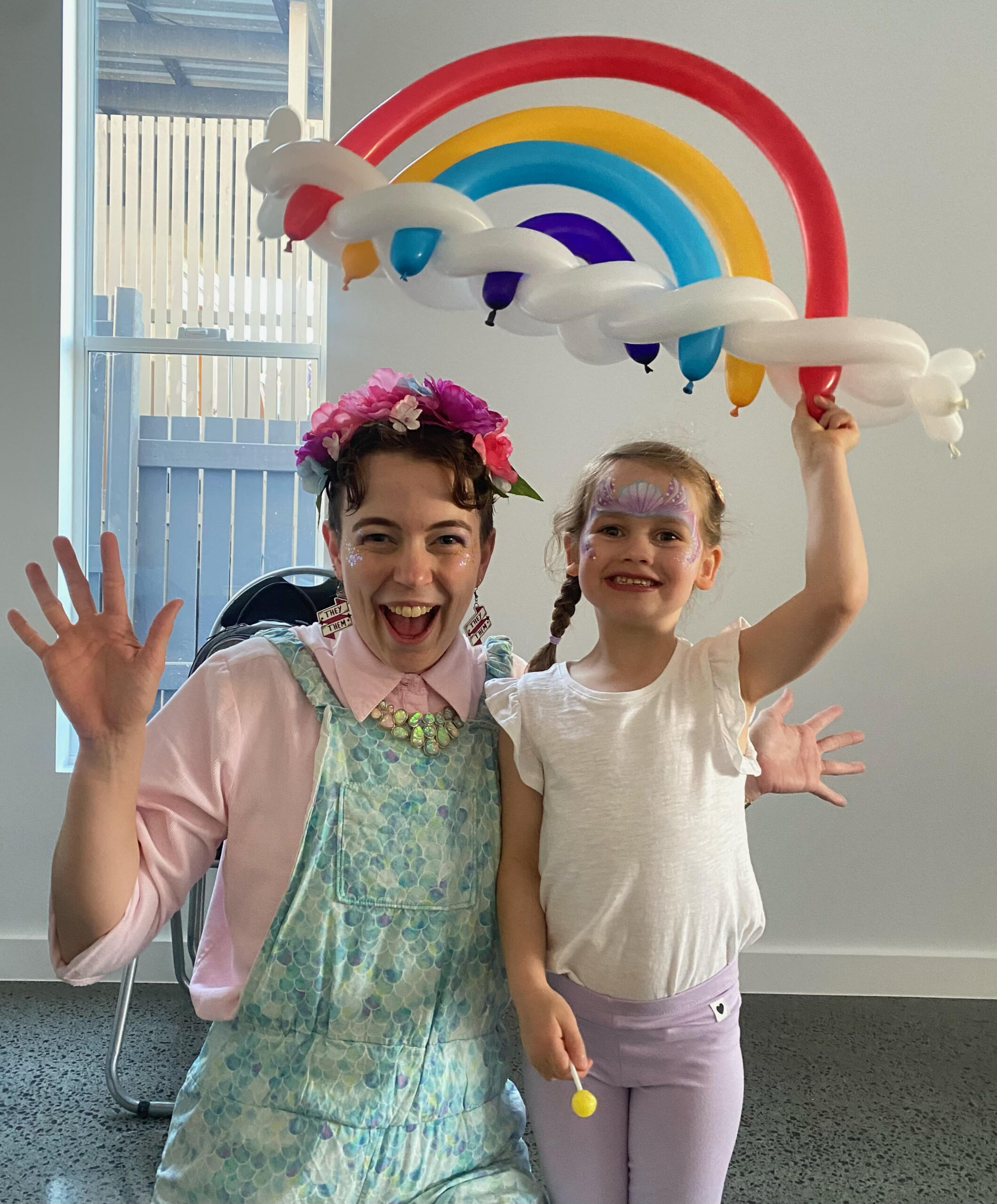 Entertainer and child pose together with a large balloon rainbow